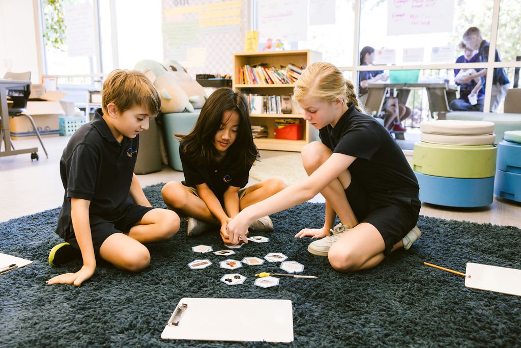 three students in school uniforms arranging cards