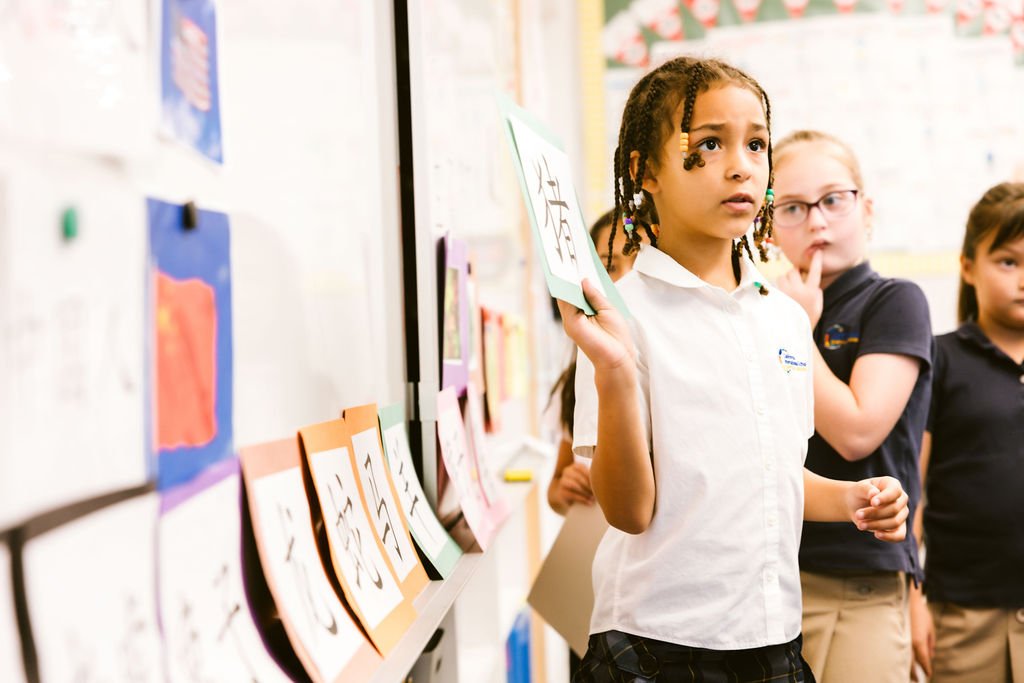 a girl raising a hand holding chinnese board